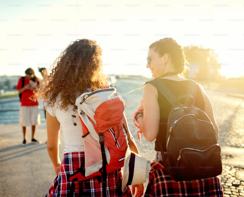 Girlfriends having conversation walking at street, sunset or morning light. Friends concept.