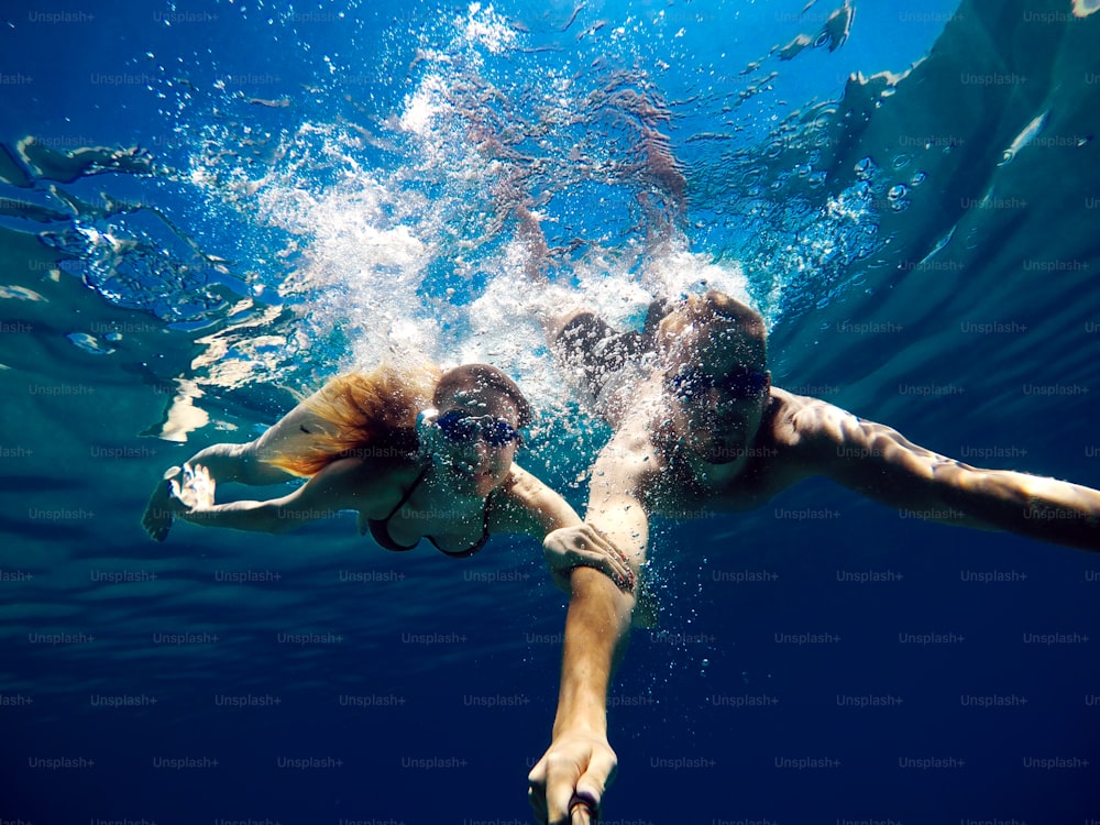 Cheerful couple having fun underwater and making selfie.