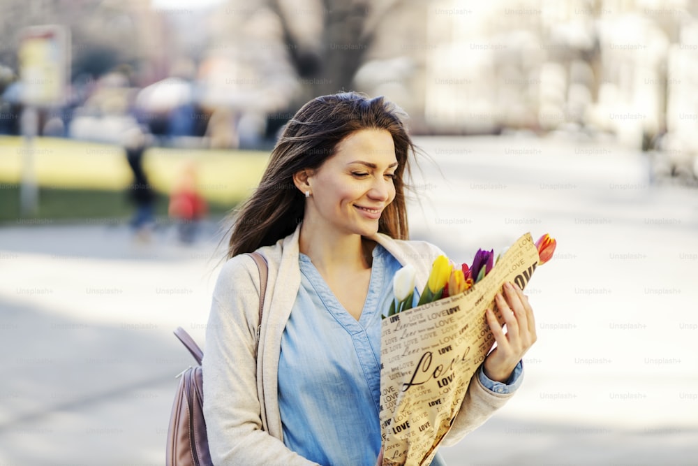 A smiling woman holding bouquet of tulips as a gift from her boyfriend.