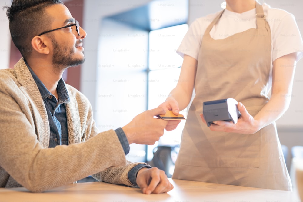 Jovem empresário elegante dando cartão de crédito de plástico para garçonete no café enquanto vai pagar o almoço