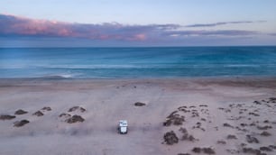 Camper van in outdoors alone camp site enjoy freedom and sunset with ocean and sky view. Concept of travel and adventure. Summer holiday vacation with modern camping car parked on the sand