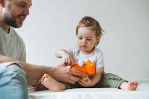 Glücklicher Vater junger Mann und kleines Mädchen kleine Tochter hat Spaß beim Spielen mit Spielzeug im Kinderzimmer zu Hause