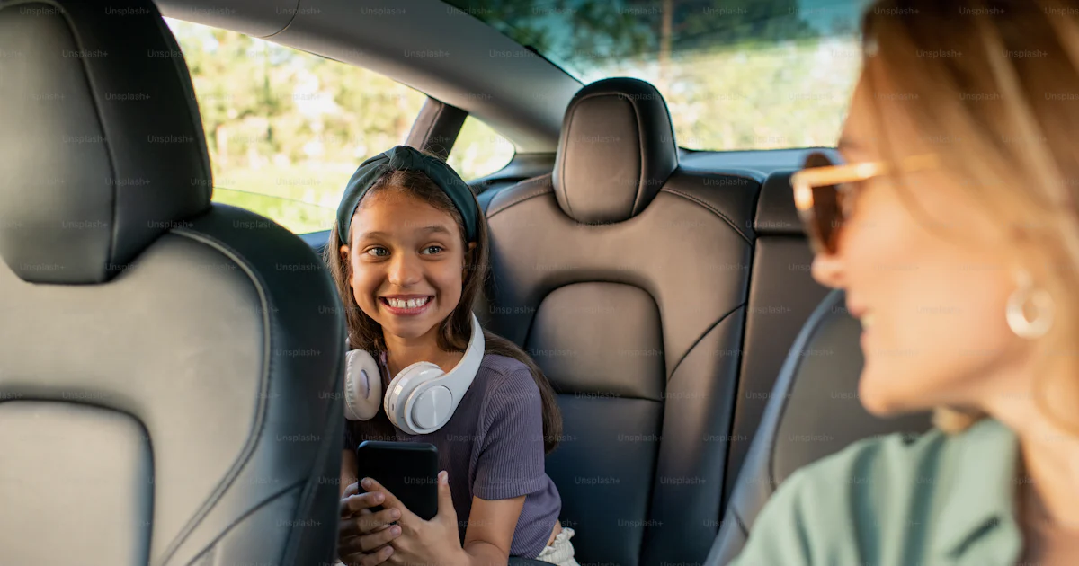 Filha feliz olhando para sua mãe enquanto sentada no banco de trás ...