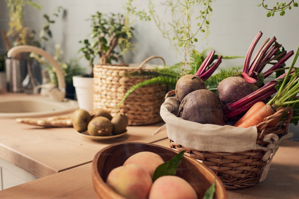 スムージーを準備するためのキッチンテーブルの上の新鮮な果物と野菜の入ったボウルとバスケット
