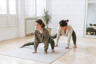 Attraktive Mutter mittleren Alters Frau und Tochter Teenager ptactice Yoga zusammen im hellen Raum