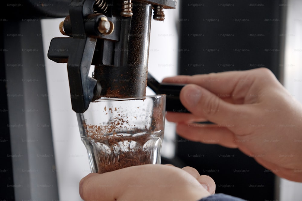 Nahaufnahme des Menschen mit der Kaffeemaschine, das Mahlen von Kaffeebohnen in Tassen, die Vorbereitung auf die Kaffeebrühuntersuchung