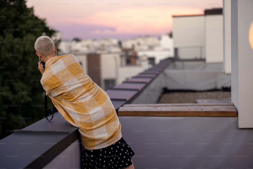 Stylish person enjoy beautiful urban view from the rooftop terrace at dusk. Friends hang out on the roof party at evening