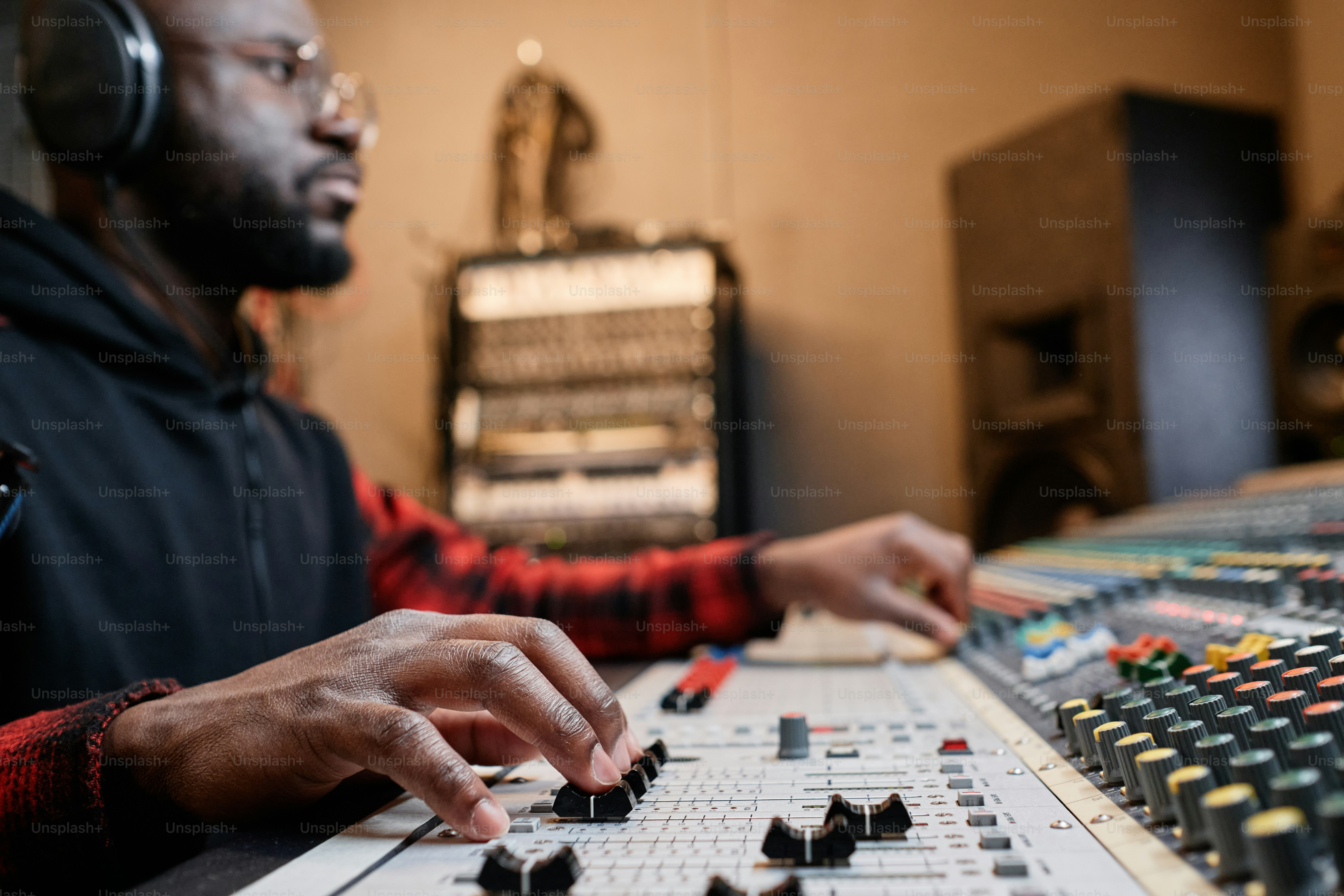 African American music producer working in record studio adjusting ...