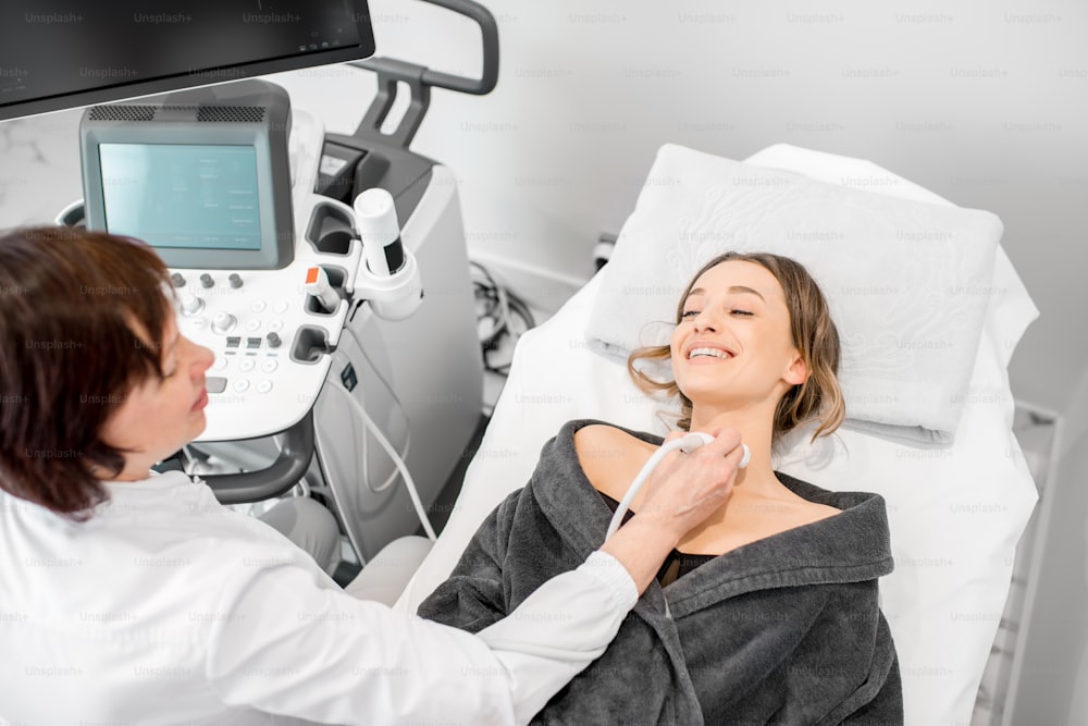Young woman patient during the ultrasound examination of a thyroid lying on the couch in medical office