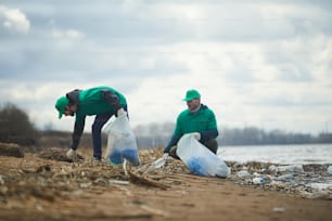Ecology organization workers picking litter from dirty territory and utilizing it into special sacks