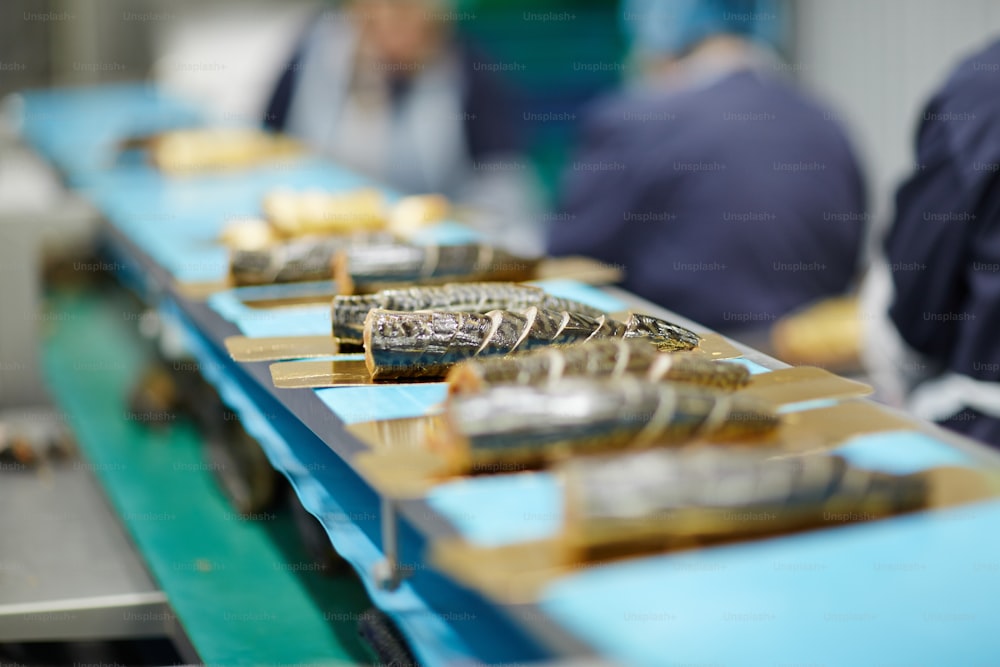 Rodajas de pescado ahumado en láminas de hojalata que avanzan en la línea de procesamiento