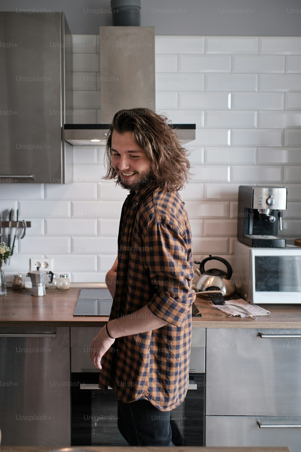 Young man standing by the kitchen furniture and looking over his shoulder