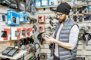 Stylish man choosing gear stars, buying bicycle parts at the small bicycle shop