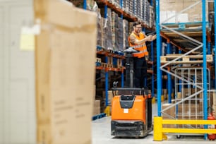 An inspector on forklift scanning boxes on shelves in warehouse.