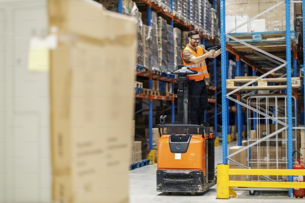 An inspector on forklift scanning boxes on shelves in warehouse.