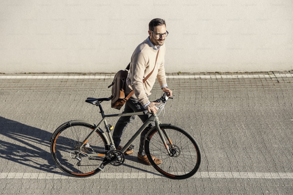 A city man pushing his bicycle and going to work. He is living sustainable lifestyle.