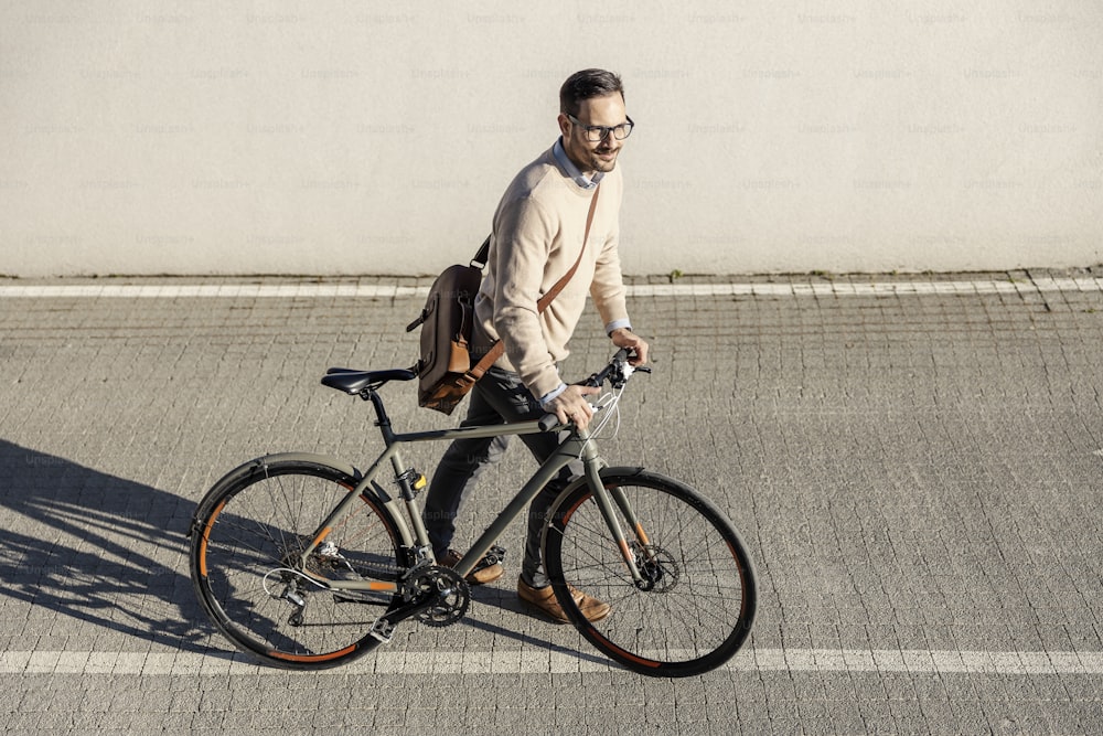 Un uomo di città che spinge la sua bicicletta e va al lavoro. Sta vivendo uno stile di vita sostenibile.