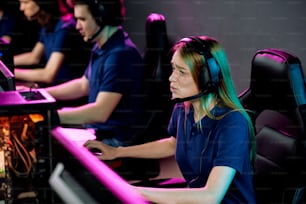 Worried E-sport girl in headset with microphone playing video game in computer club