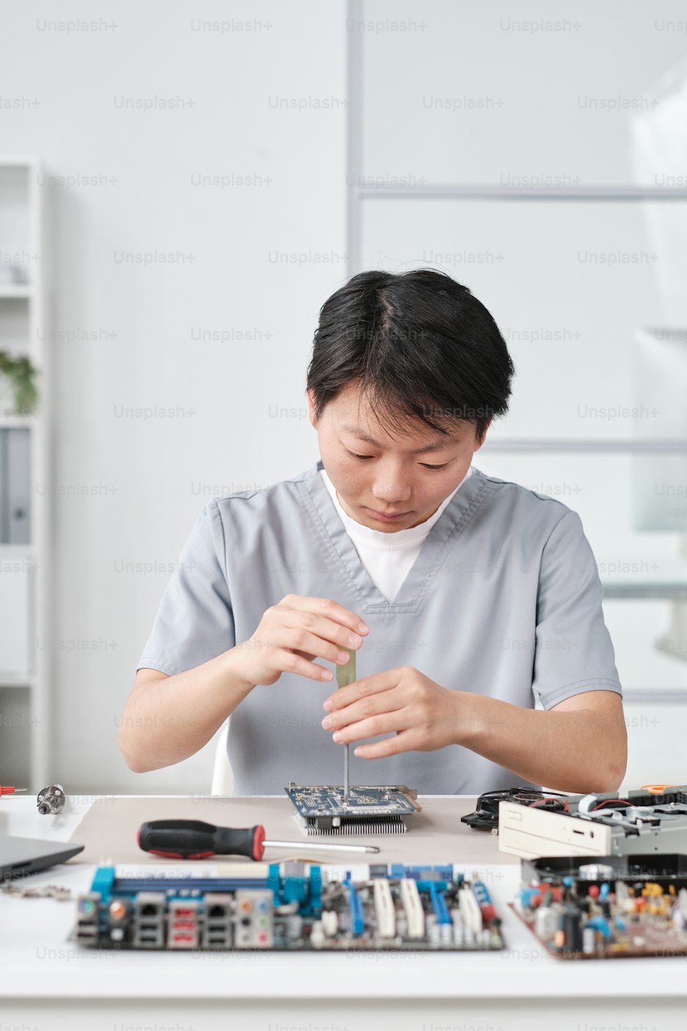 Young chinese female worker of maintenance service repairing motherboard or other hardware