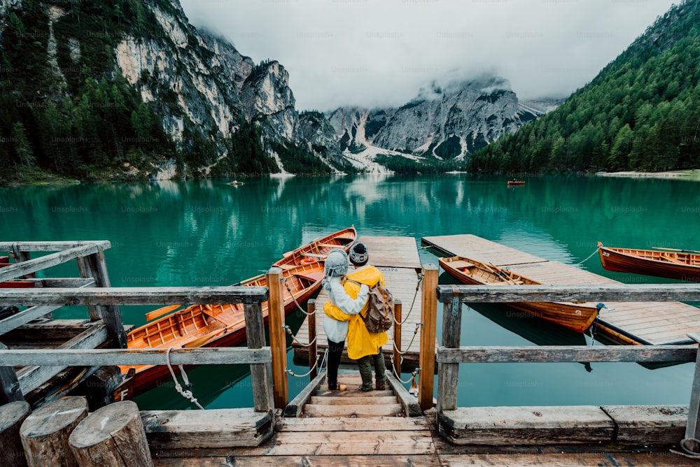 Romantic couple on a boat visiting an alpine lake at Braies Italy. Tourist in love spending loving moments together at autumn mountains. Concept about travel, couple and wanderust.