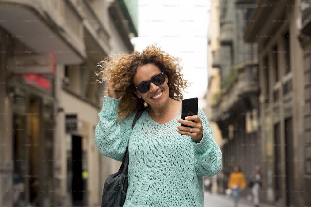 Portrait f cheerful adult beautiful woman do phone call with modern technology cellular walking in the street in the city - concept of outdoor urban place leisure activity and trendy people smiling and enjoying