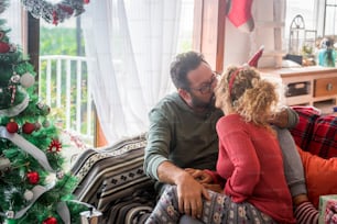 Adult couple caucasian people in love kissing and sharing sweetness at home during christmas winter holidays - concept of celebration and life together forever with happy man and woman kiss each other