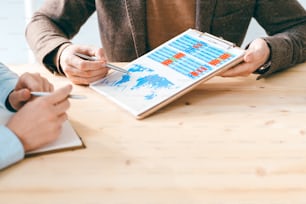 Un homme d’affaires contemporain montre à un collègue un document avec un tableau ou un graphique financier pendant la discussion des données