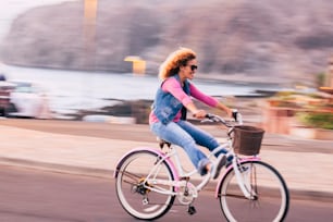 Imagen borrosa y en movimiento con una joven alegre y alegre que disfruta de un paseo en bicicleta y se divierte al aire libre - concepto de personas de estilo de vida activo de la felicidad con la mujer que disfruta de la bicicleta
