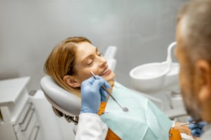 Portrait of a beautiful and cheerful woman sitting as a patient on the dental chair during a medical examination at the dental office