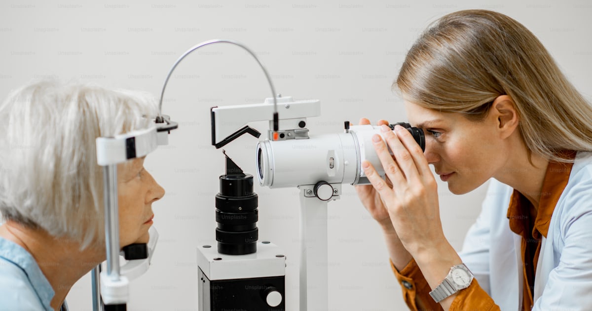 Ophthalmologist examining eyes of a senior patient using microscope ...