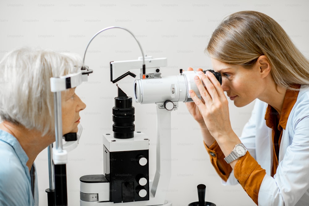 眼科での診察中に顕微鏡で高齢患者の目を診察する眼科医