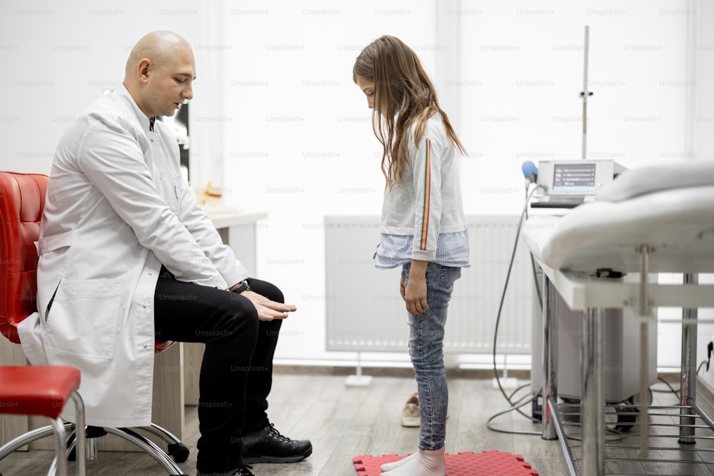 Physical therapist examines little girl in detail for musculoskeletal disorders in medical office. Concept of pediatrics and examination of musculoskeletal child's system