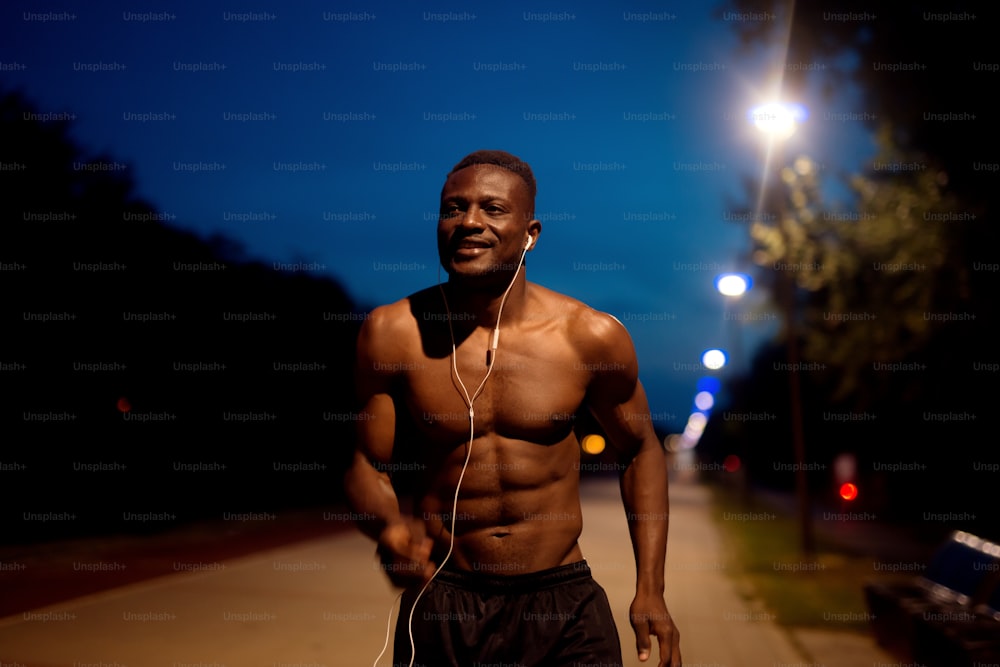 Afro-americano fitness homem bonito treinando. Correr à noite..