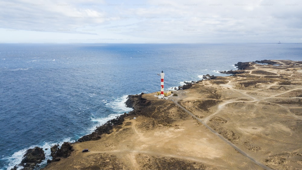 aerial point of view of lighthouse on the coast to make light on the ocean for ships. many roads to go everywhere and discover places in the desert. travel adventure concept