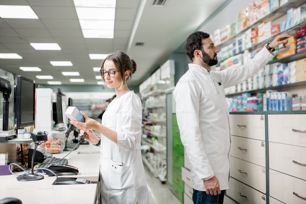 Man and woman pharmacists working at the cash register of the modern pharmacy store