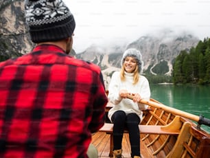 Romantic couple on a boat visiting an alpine lake at Braies Italy. Tourist in love spending loving moments together at autumn mountains. Concept about travel, couple and wanderust.