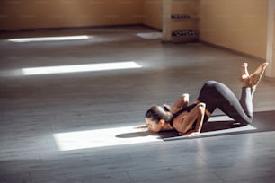 Joven yogui atractiva y delgada dedicada en postura de yoga de ocho puntos. Interior del estudio de yoga.