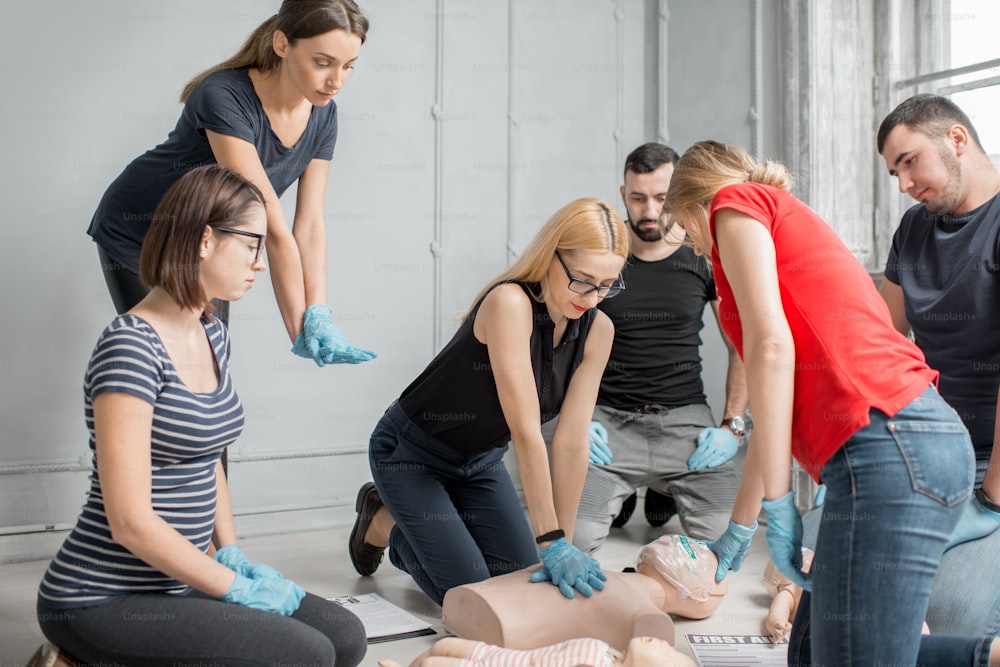 Groupe de personnes apprenant à faire des compressions cardiaques de premiers secours avec des mannequins pendant la formation à l’intérieur