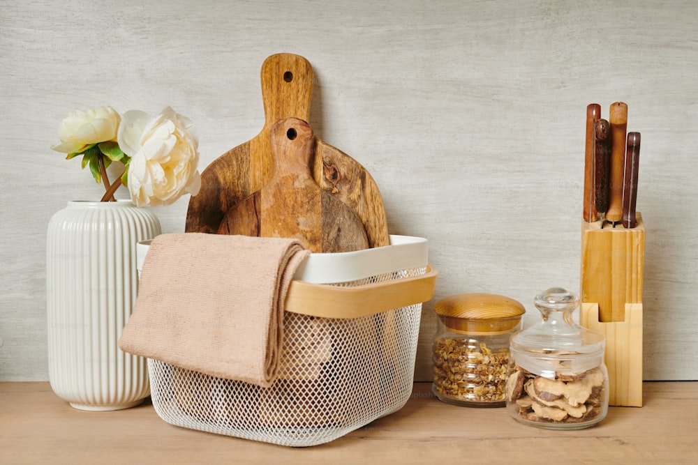 Two wooden chopping boards and towels in a basket next to a vase of flowers