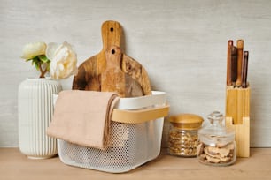 Two wooden chopping boards and towels in a basket next to a vase of flowers