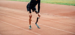 Müder Läufer mit Beinprothese, der auf der Laufstrecke steht und eine Pause macht.