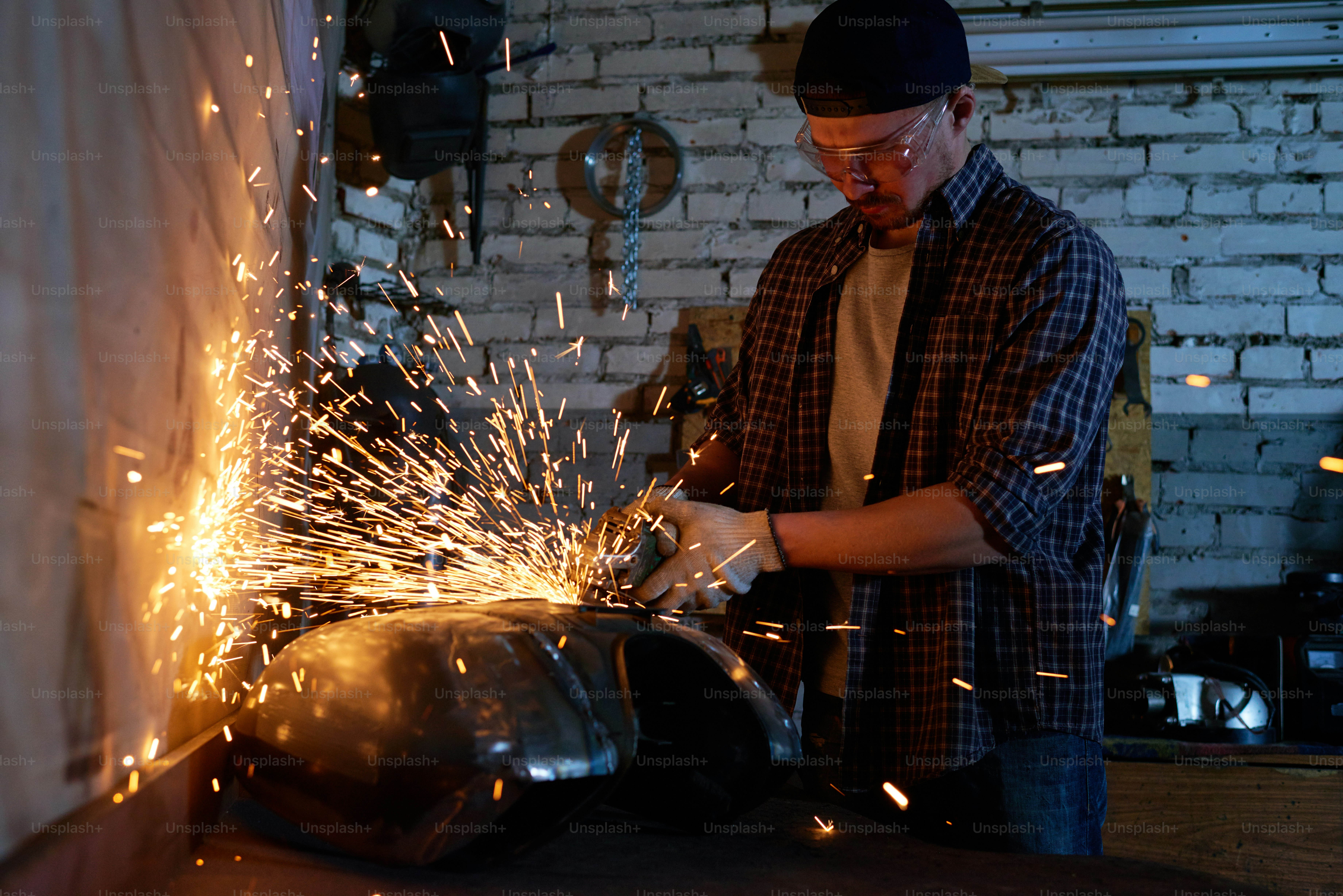 Young repairman grinding motorbike fuel tank part in his horizontal shot photo Free