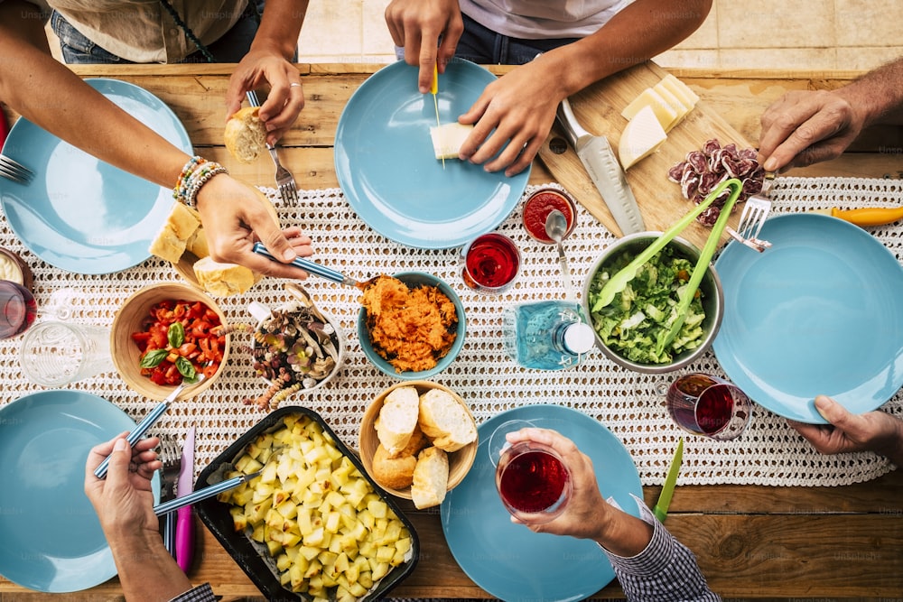 Menschen, die zusammen in Freundschaft oder Familienfeier mit Tisch voller Essen von vertikal oben gesehen werden - Freunde und haben Spaß Konzept - Farben und Hintergrund mit Holztisch