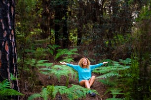 Jeune femme en bonne santé méditer et faire la position de yoga au milieu d’une belle forêt sauvage verte - aimez le concept de la journée de la terre et de la planète avec des personnes environnementales profitant de la nature boisée en plein air