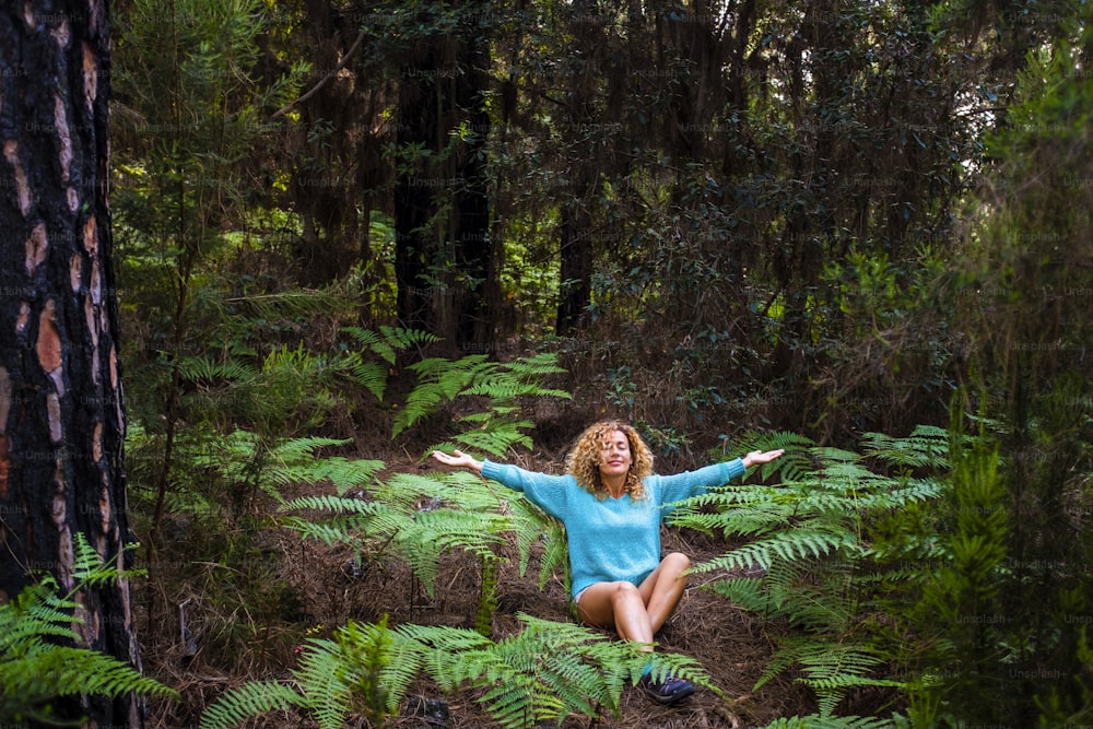 Jovem mulher saudável meditar e fazer yoga posição no meio de uma bela floresta selvagem verde - amo dia da Terra e conceito de planeta com pessoas ambientais desfrutando da natureza de madeira ao ar livre