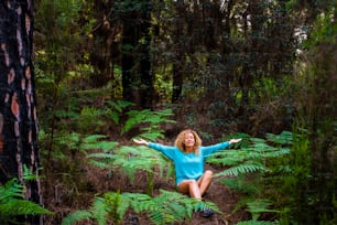 Young healthy woman meditate and do yoga position in the middle of a green wild beautiful forest - love earth's day and planet concept with environmental people enjoying the wood nature outdoor