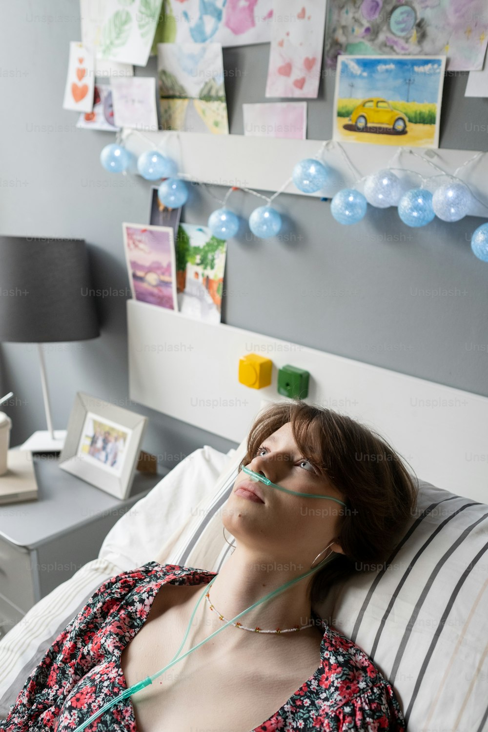 現代の病棟のベッドに横たわっている間、酸素鼻パイプを持つ安らかな十代の女の子が枕に頭を置いています