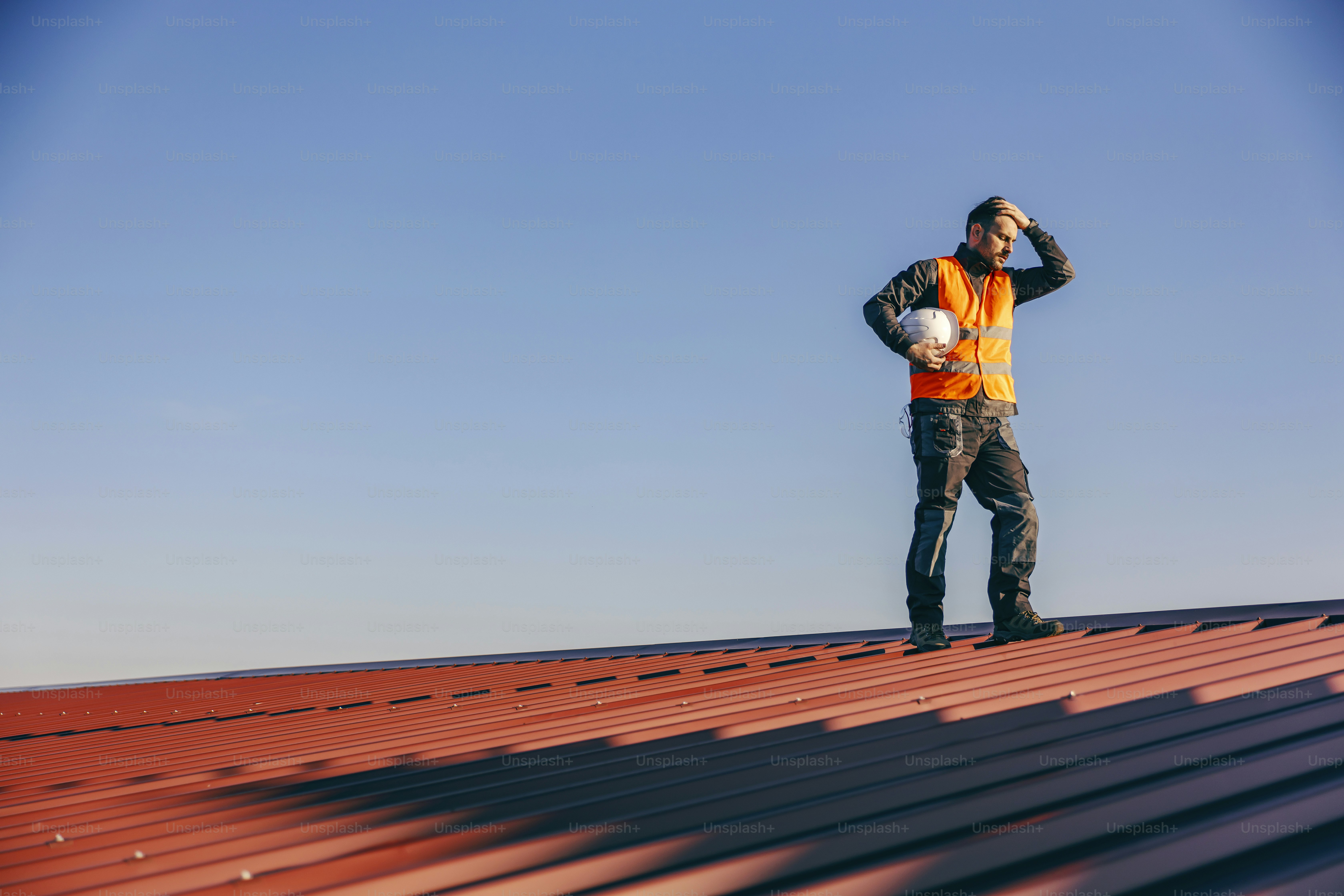 A construction worker holding his head and having troubles at work