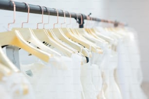 Clothing rack with wedding dresses on golden hangers in row, wedding show room concept