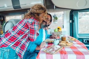 Happy traveler couple hug with love and fun together inside a camper van motor home. People using rv vehicle for travel and enjoy holiday vacation on the road. Van life off grid lifestyle caucasian